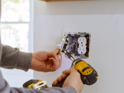 Work on installing electrical outlets with electrical wires and connector installed in plasterboard drywall
