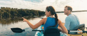 Kayak Eco Tour tourists kayaking in the mangroves of the Everglades, Keys, Florida, USA travel. Happy man and woman looking at the wildlife in nature. Panoramic banner crop.